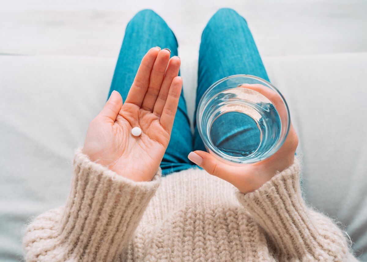 woman holding medicine and glass of water